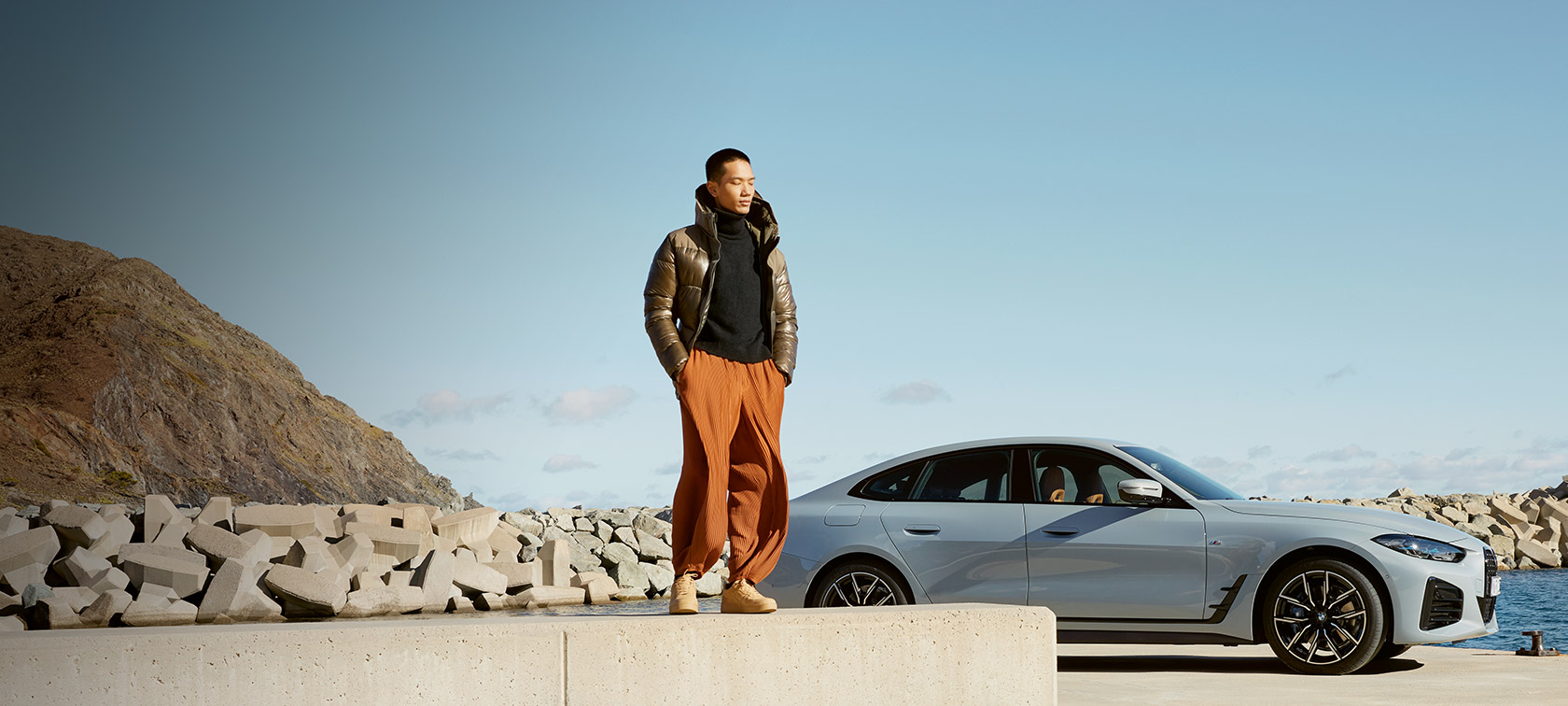 BMW Service Inclusive, hombre delante de un BMW i4 en la costa